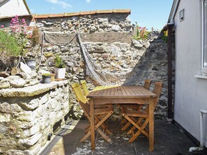 Eine Steinsäule mit einer Hängematte und einem Holztisch mit Stühlen.