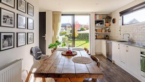 Una cucina moderna con tavolo da pranzo in legno, mobili bianchi e vista sul giardino.