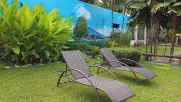 Uma área de jardim com duas cadeiras de descanso e um mural na parede.