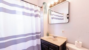 A bathroom with a striped shower curtain, a sink with a mirror above it, and a toilet.