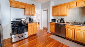 A modern kitchen with wooden cabinets, stainless steel appliances, and a wooden floor.