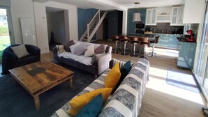 A spacious living room with a sofa, a coffee table, and a staircase leading to a kitchen area.