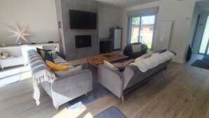 A modern living room with a sofa set, a coffee table, and a TV mounted on the wall.