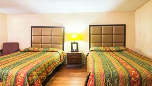 A hotel room with two beds, a nightstand, a lamp, and a chair. - Bama Motel Mobile I-65 & US-90 (Mobile)