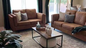 Un salon avec deux canapés en cuir marron, une table basse et une grande plante en pot.