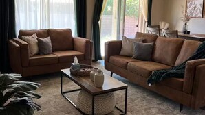 Un salon avec deux canapés en cuir marron, une table basse et un ventilateur de plafond.