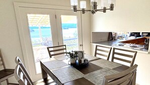 A dining area with a rectangular table, six wooden chairs, and a chandelier. - New! Charming Blue Haven Cottage with Amazing Lake Pend Oreille Views! (Hope)
