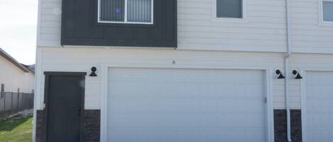 A two-story house with a dark front facade, two garage doors, and a small balcony.