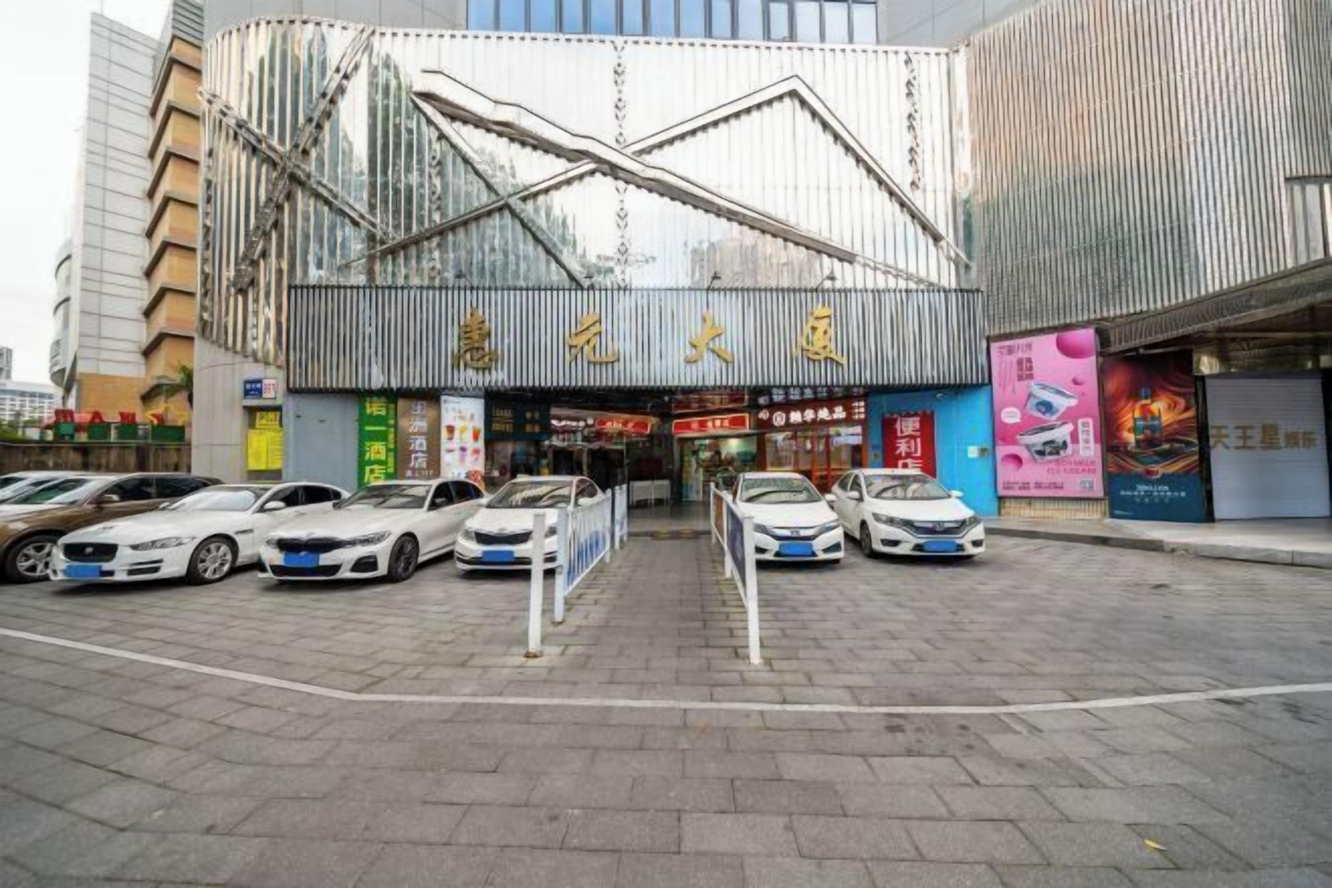Un edificio moderno con una entrada destacada y varios coches aparcados delante.