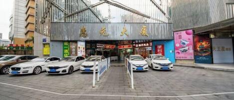 Un edificio moderno con una entrada destacada y varios coches aparcados delante.