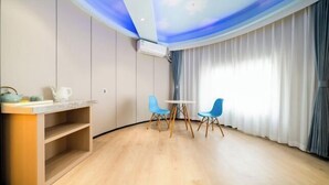 A modern room with a wooden floor, a small table with chairs, an air conditioning unit, and a window with curtains. - Bedola Hotel (Xiamen Railway Station Mingfa Plaza) (Xiamen)