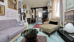 A living room with a sofa, armchair, coffee table, and artwork on the walls.