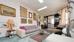 A living room with a sofa, a coffee table, a rug, and various framed artworks on the walls.