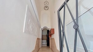 A staircase leading to a room with a large window and a decorative ceiling light.