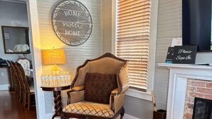 Una sala de estar con una mesa de centro redonda de vidrio, un sillón marrón, una lámpara y un letrero que dice 'HOGAR dulce HOGAR'.