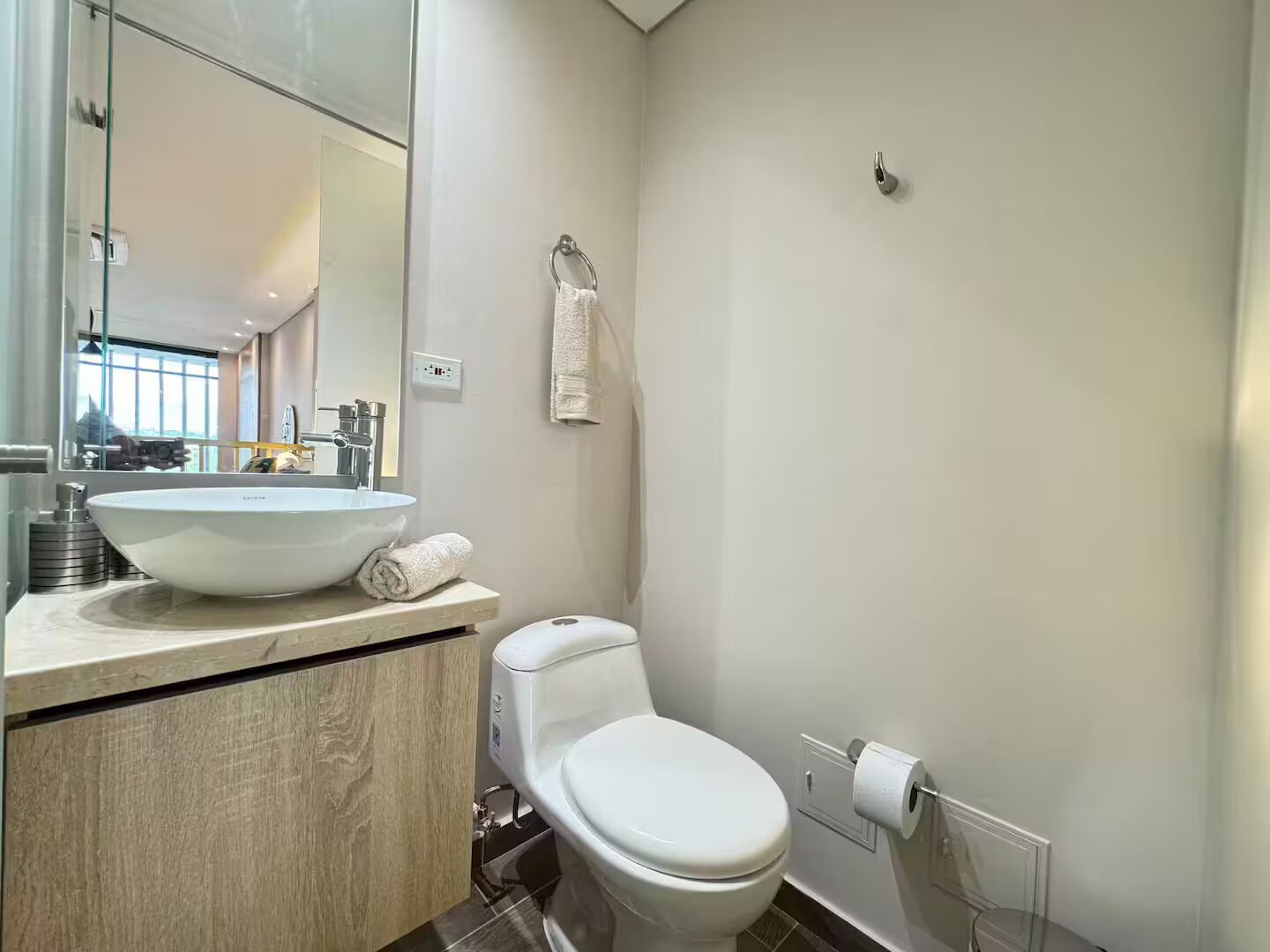 Un baño moderno con un lavamanos blanco grande, un inodoro y un espejo.