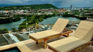 Area piscina con due sdraio e vista sulla città e sul fiume.
