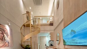 Un'ampia zona giorno con scala a chiocciola, un'ampia televisione a schermo piatto e un angolo salotto accogliente.