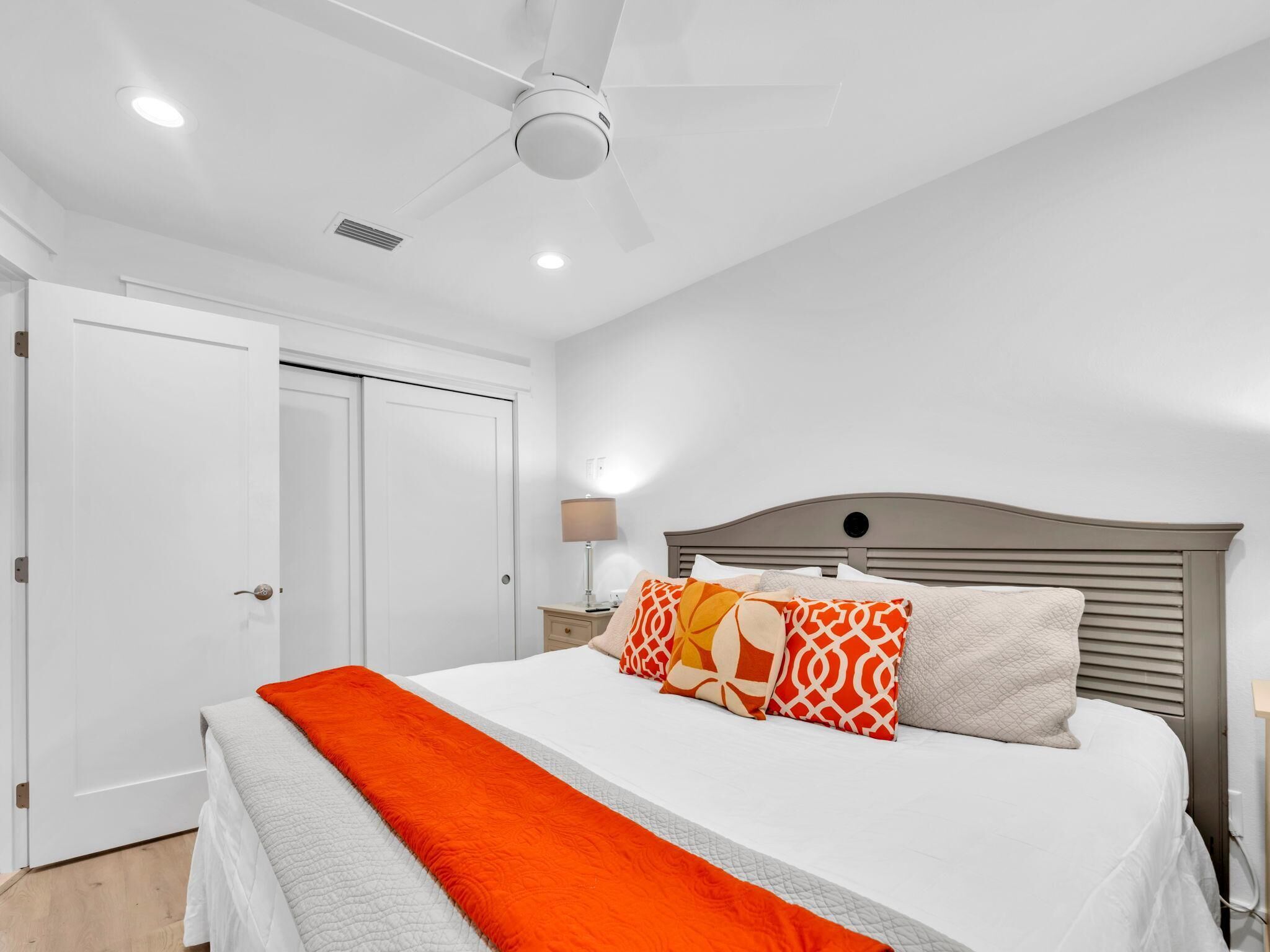 A bedroom with a bed, a ceiling fan, a nightstand, and a lamp.