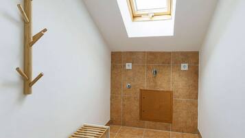 Ein kleiner Raum mit geneigtem Dach, einer Dachkuppel, einer Holzbank und einem an der Wand befestigten Regal.