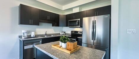 Enjoy cooking in this well-equipped kitchen with a refrigerator, microwave, and granite countertop.