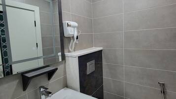A modern bathroom with a white sink, a toilet, and a shower.