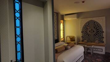 A bedroom with a bed, a bench, and a patterned carpet.