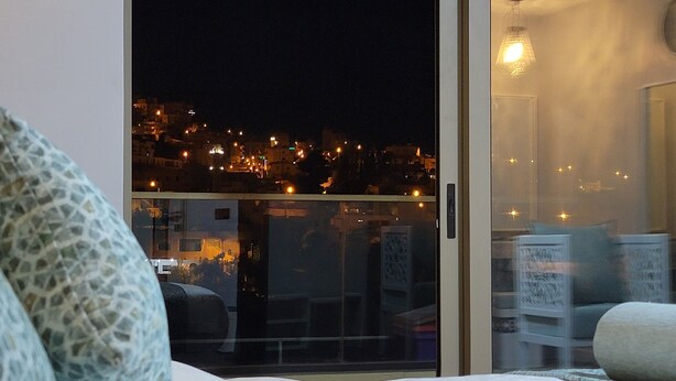 A hotel room with a bed, a view of the city at night, and a decorative white partition.