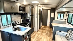 A compact RV kitchen with a stove, sink, and microwave. - Camper in Zephyrhills with Wi-Fi (Zephyrhills)