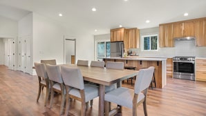 A modern kitchen with wooden cabinets, a stainless steel refrigerator, and a built-in oven. - Book Your Mt. Baker Après Ski Stay (Deming)
