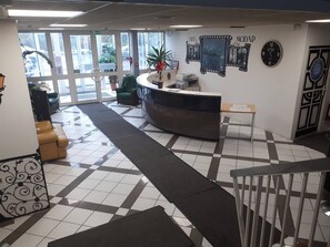 Un espace d’accueil comprenant un comptoir d’enregistrement, une horloge et une grande fenêtre.