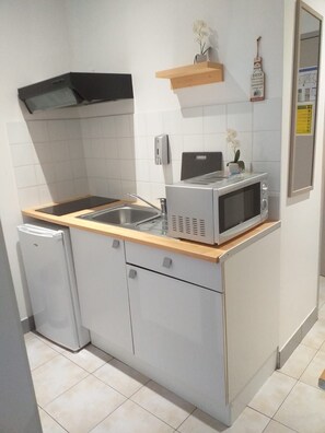 A compact kitchen with a microwave, sink, and a small refrigerator. - Appart Hotel (Champagne-sur-Oise)