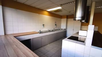 A modern kitchen with white tiles, grey cabinets, and a wooden countertop.