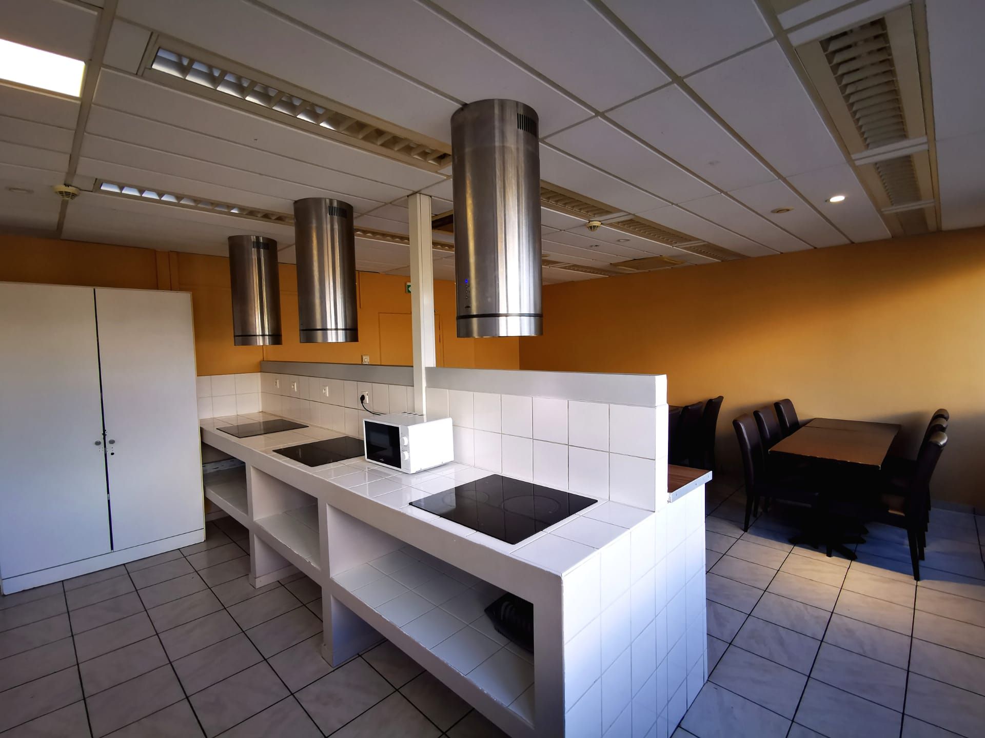 Cocina moderna con una isla central, extractor de acero inoxidable y comedor con mesa y sillas.