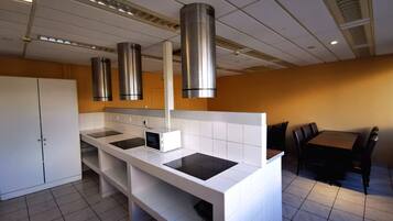 Cocina moderna con una isla central, extractor de acero inoxidable y comedor con mesa y sillas.