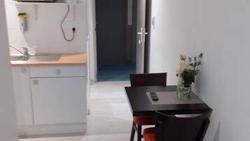 Un couloir étroit mène à un coin repas comprenant une table et des chaises, un four à micro-ondes et un petit espace cuisine.