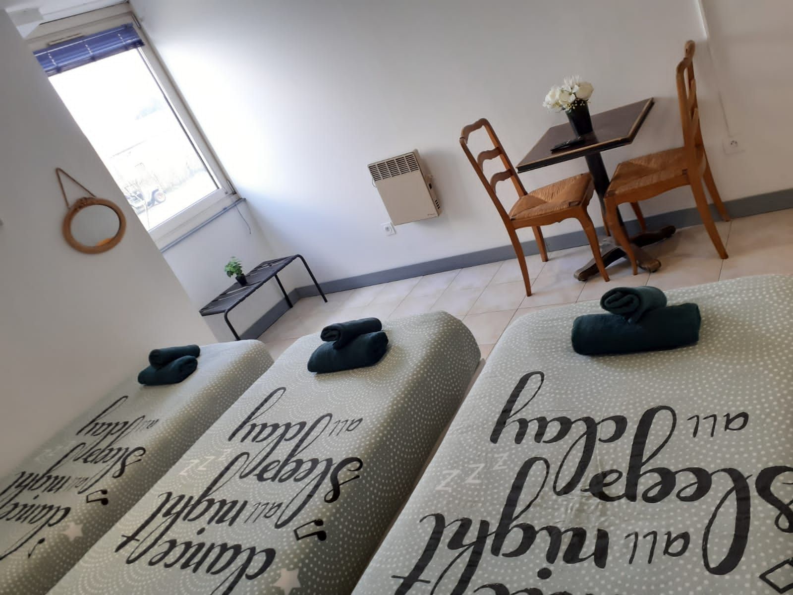 Una habitación de hotel con cama, una mesita con un florero y una silla.