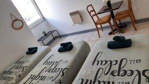 A hotel room with a bed, a small table with a vase of flowers, and a chair. - Appart Hotel (Champagne-sur-Oise)