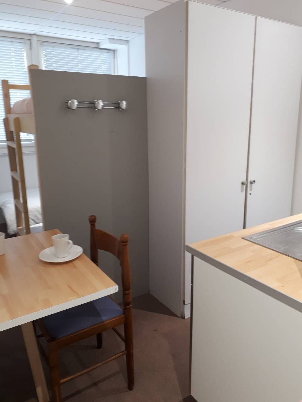 A small kitchenette with a wooden table, a chair, and a cabinet.