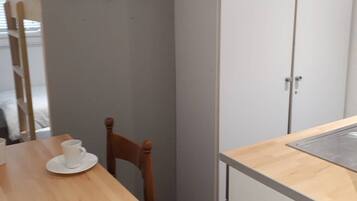 A small kitchenette with a wooden table, a chair, and a cabinet.