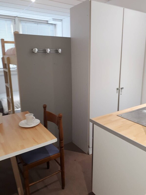 A small kitchenette with a wooden table, a chair, and a cabinet. - Appart Hotel (Champagne-sur-Oise)