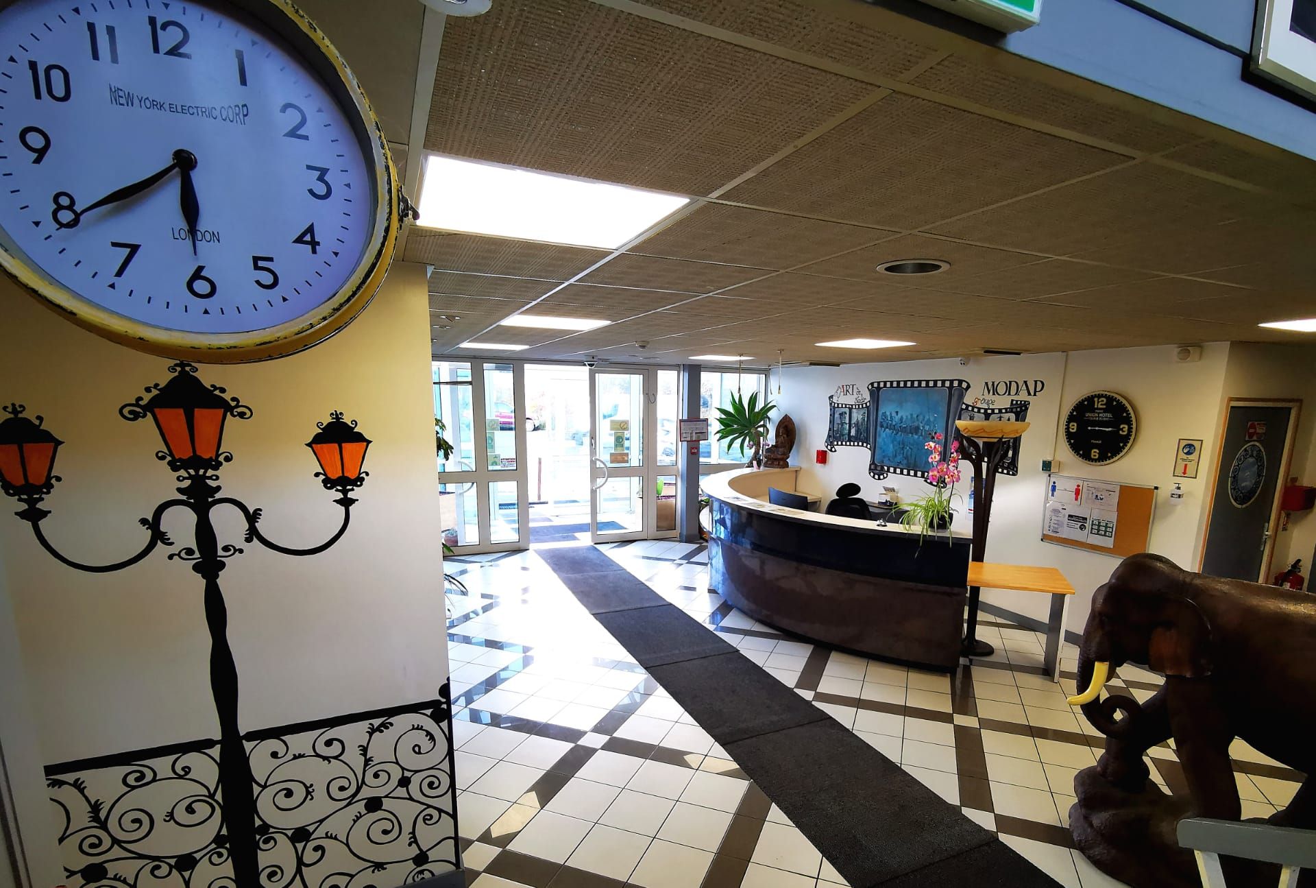 A reception area with a clock, a reception desk, a decorative lamp, and a wall-mounted clock.