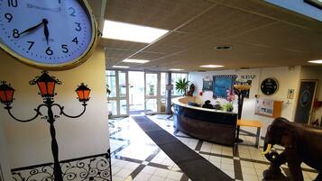 A reception area with a clock, a reception desk, a decorative lamp, and a wall-mounted clock.