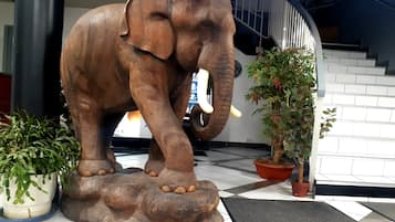 A large elephant statue on a platform with potted plants around it.