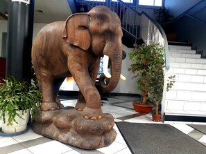 A large elephant statue on a platform with potted plants around it. - Appart Hotel (Champagne-sur-Oise)