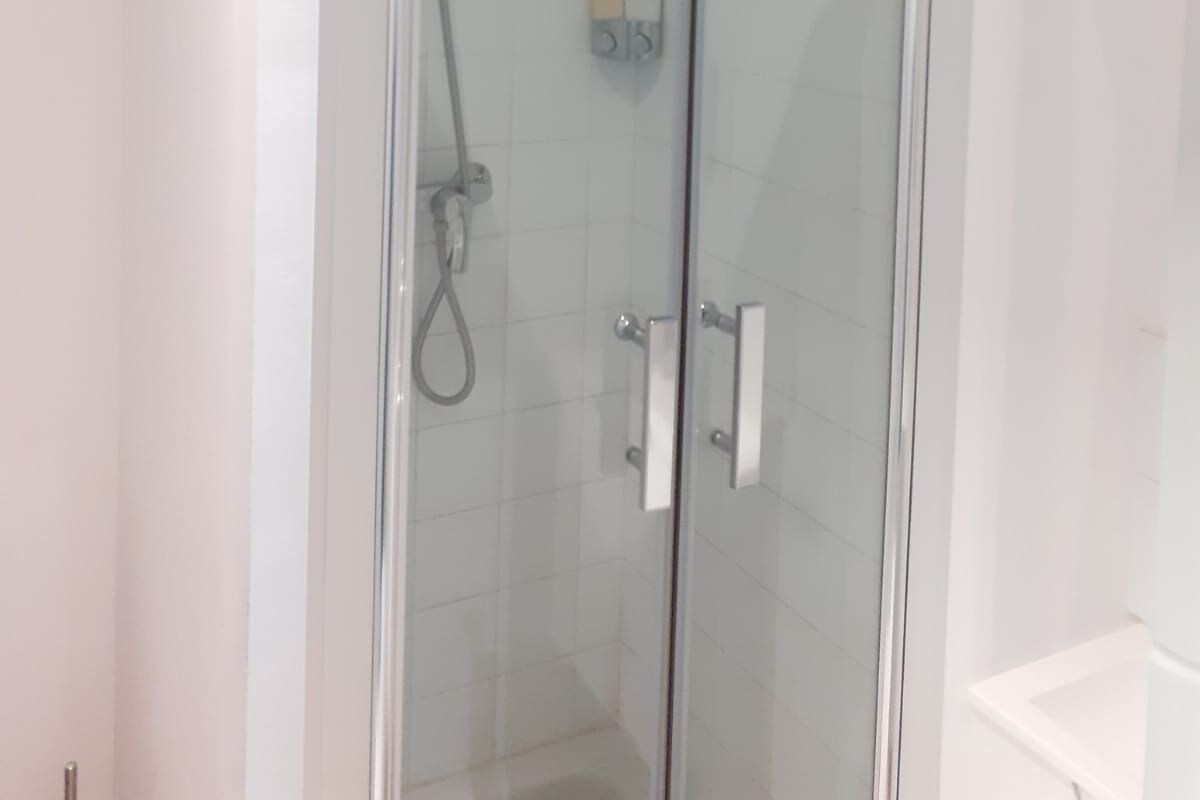 A glass-enclosed shower area with a control panel and a white towel hanging on the door.