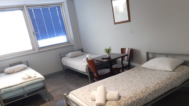 A small, clean room with two single beds, a table, and a chair. - Appart Hotel (Champagne-sur-Oise)