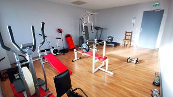 A gym with cardio machines, weightlifting equipment, and a wooden floor.