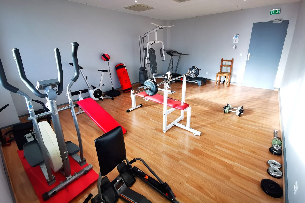 A gym with cardio machines, weightlifting equipment, and a wooden floor.