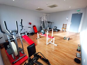 Un gimnasio con máquinas de cardio, equipo de levantamiento de pesas y suelo de madera.